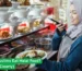 A woman serving halal food at a restaurant counter, explaining whether non-Muslims can eat halal meals prepared with care and hygiene